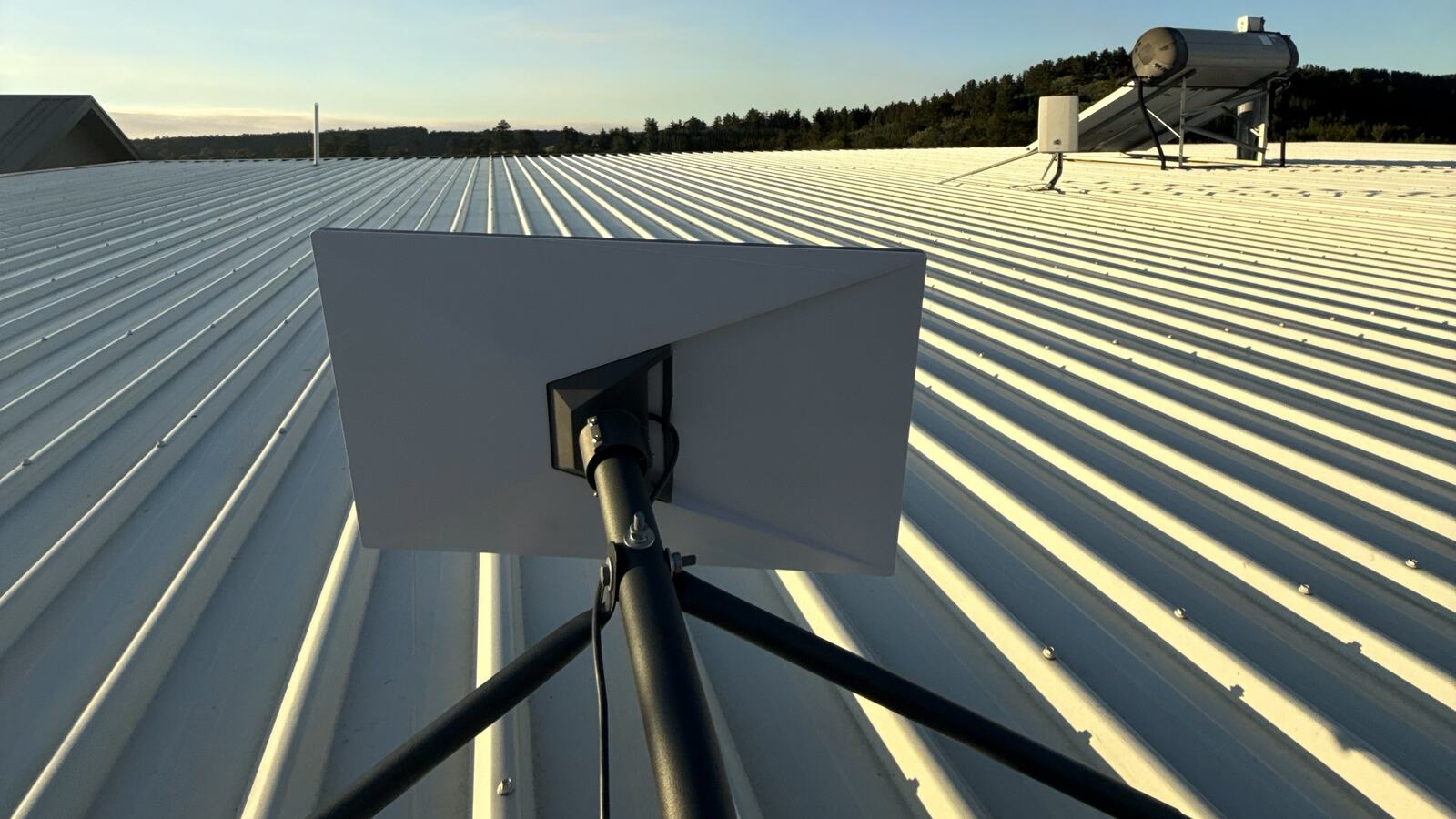 Starlink dish installed on a metal roof at golden hour, looking out over bushland in the South West of WA